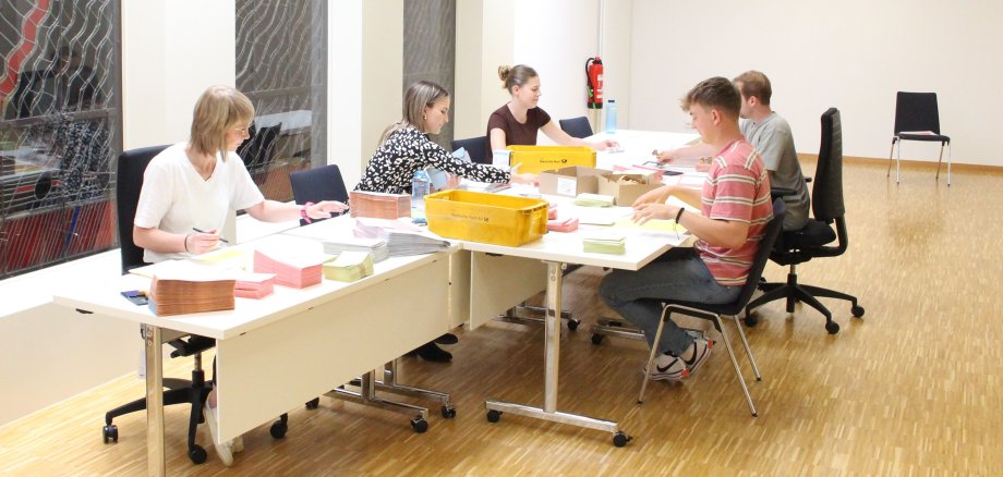 Das Foto zeigt Mitarbeiter der Verwaltung bei der Verpackung der Wahlunterlagen.